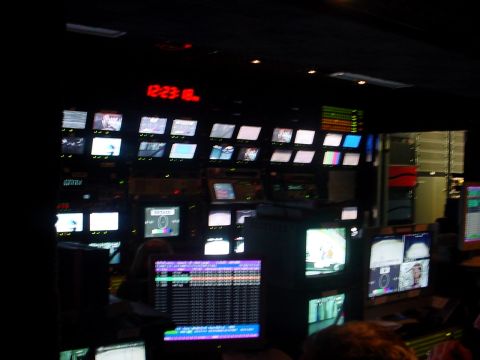 2000 Ford Taurus - A busy control room is filled with monitors displaying various feeds, with a digital clock showing 12:23.