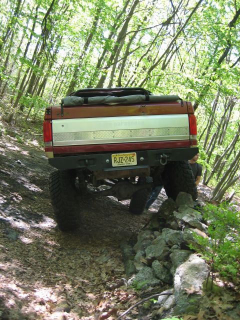 1990 Ford Bronco - 1990 Ford Bronco navigating a rocky, wooded trail.