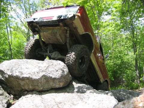 1990 Ford Bronco - An off-road vehicle navigates a rocky trail, demonstrating its suspension and tire grip.