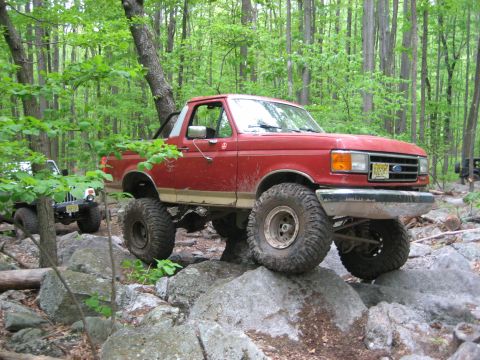 1990 Ford Bronco - This lifted 1990 Ford Bronco navigates a rocky trail in a wooded area.