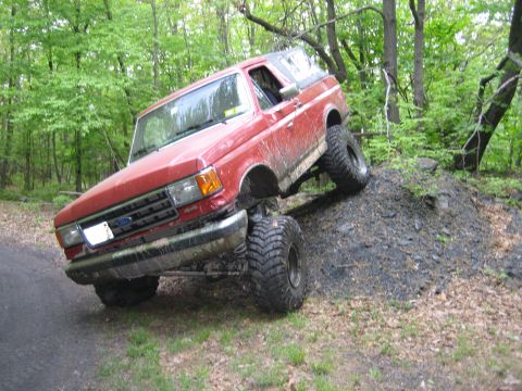 1990 Ford Bronco - 1990 Ford Bronco navigating an off-road trail with steep inclines.