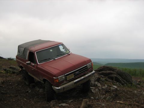 1990 Ford Bronco - 1990 Ford Bronco navigating a challenging off-road terrain on a cloudy day.