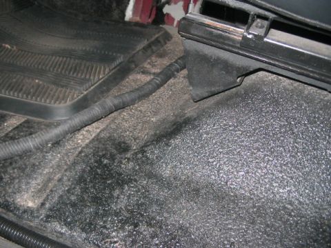 1991 Ford Bronco - Close-up view of the interior floor and a seat bracket, showing a wiring harness running along the carpet.