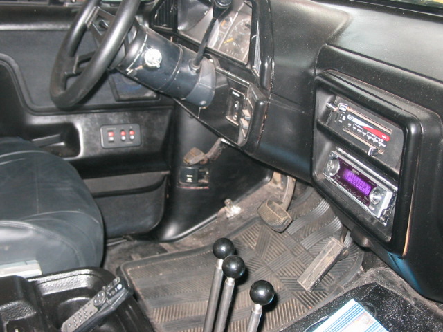 1991 Ford Bronco interior showing dashboard, steering wheel, two radios, and three gear shifters