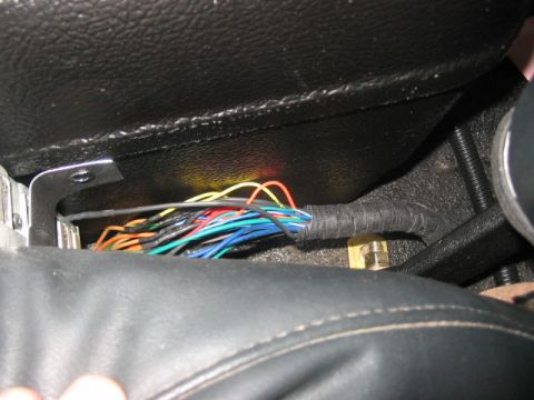 1991 Ford Bronco - This image shows a messy bundle of wires, likely from an aftermarket installation, located beneath the vehicle's interior seating area.