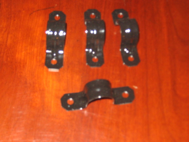 Four black metal hose clamps on a wooden surface