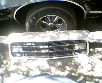 1973 Ford Ranchero - Close-up of a vehicle's grille and wheel, possibly a part from a larger assembly.