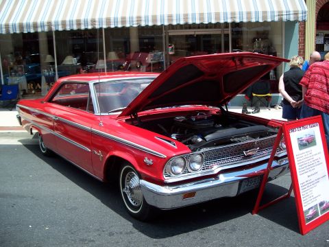 1971 Ford Ranchero - A red 1963-1964 Ford Galaxie is displayed with its hood open, accompanied by an informational sign.