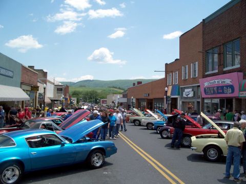 1971 Ford Ranchero - A street fair or car show is taking place with many classic cars on display.