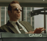 1987 Suzuki Samurai - A man wearing sunglasses and a suit plays a Casio keyboard in front of a microphone.