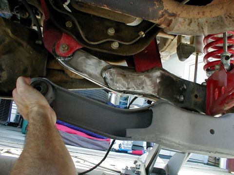 1996 Ford Bronco - Front suspension component being worked on, showing welds and a hand holding the control arm.