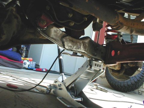 1996 Ford Bronco - Close-up of a vehicle's suspension system, showing a metal arm and a red coil spring.
