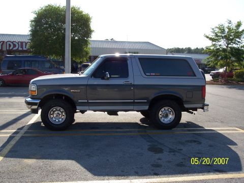 1996 Ford Bronco - A two-tone gray 1996 Ford Bronco is parked in a lot with other vehicles visible.