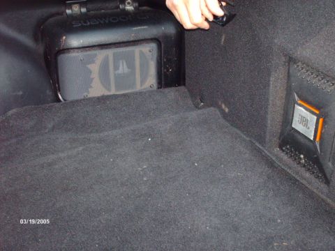 1995 Ford Probe - The trunk of a car features aftermarket audio equipment, including a JL Audio subwoofer and a JBL speaker.