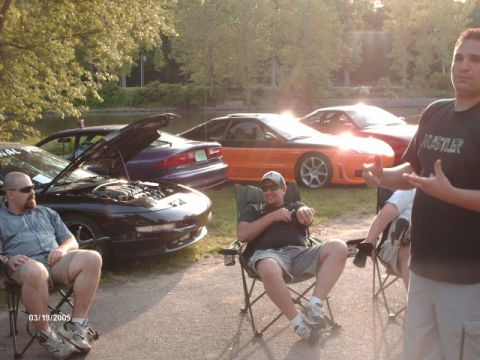 1995 Ford Probe - Several people relax outdoors near a collection of cars, one with its hood up.