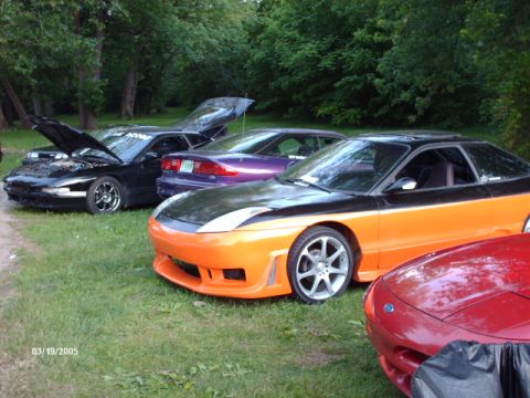 1995 Ford Probe - Several Ford Probes are parked on grass with trees in the background.