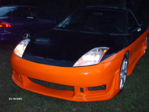 1995 Ford Probe - Customized sports car with orange front bumper and black hood, parked outdoors at night.