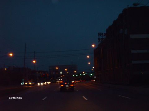 1995 Ford Probe - A car drives down a highway at dusk, with streetlights illuminating the road.
