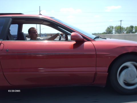 1995 Ford Probe - A red 1995 Ford Probe is seen from the side while driving on a highway with a driver behind the wheel.