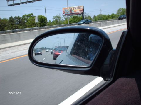 1995 Ford Probe - Traffic moves along a highway, as seen through the side mirror of a vehicle.