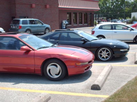 1995 Ford Probe - Two Ford Probes, a red and a black model, are parked side-by-side in a parking lot.