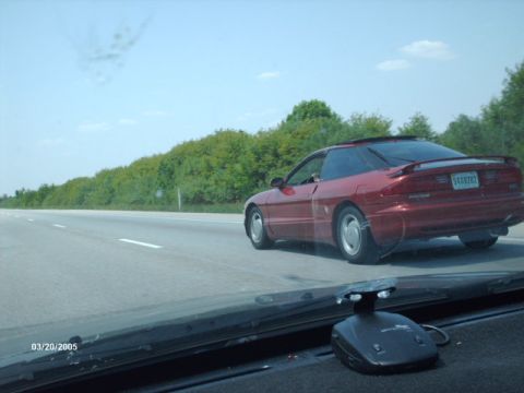 1995 Ford Probe - A red 1995 Ford Probe is seen from the side and rear as it travels down a highway.