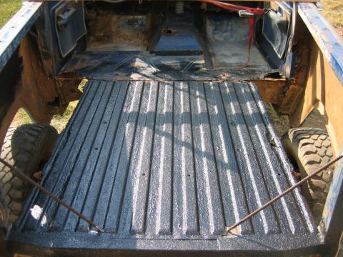 1992 Ford Mustang - The interior of a truck bed shows signs of wear and rust, with the ribbed flooring recently coated.
