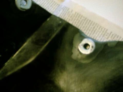1976 Ford Ranchero - A close-up view of a car part, possibly a fender liner, with masking tape and bolts attached.