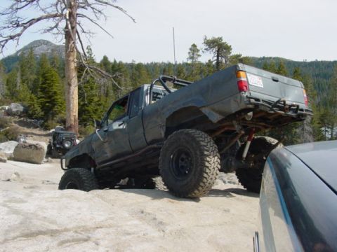 1986 Ford Bronco - This modified pickup truck is navigating a rocky trail with another vehicle in the background.