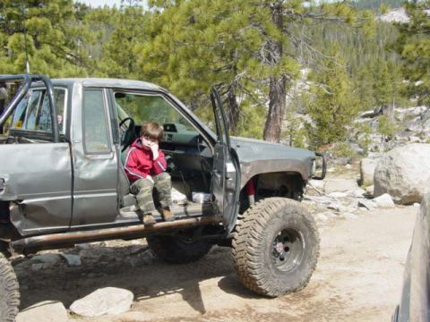 1986 Ford Bronco - Child sits in the driver's seat of a modified off-road pickup truck during an outdoor excursion.