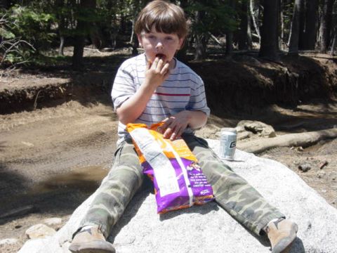 1986 Ford Bronco - A young boy enjoys a bag of chips and a soda while taking a break outdoors.