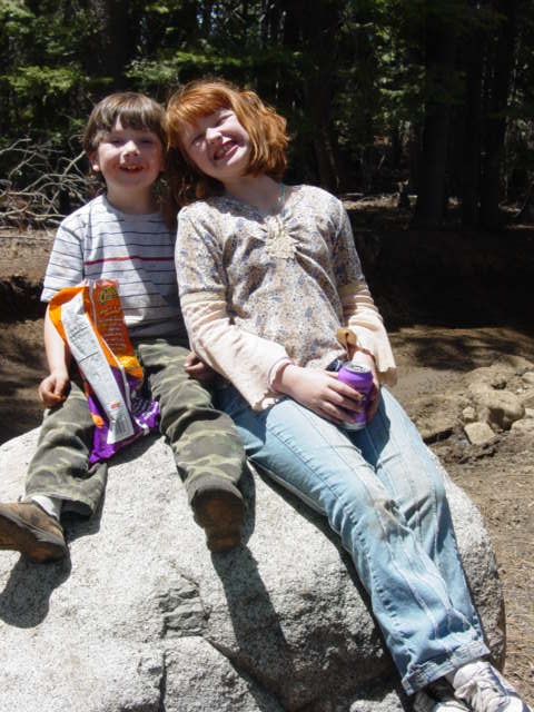 1986 Ford Bronco - Two children enjoy a moment together while sitting on a large rock in a wooded area.