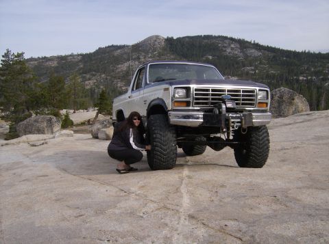 1986 Ford Bronco - A lifted 1980 Ford Bronco sits on rocky terrain, a woman crouches by its front tire.
