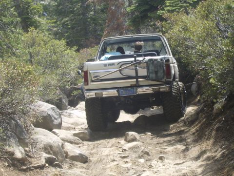 1986 Ford Bronco - A white Ford Bronco navigates a challenging, rocky off-road trail.