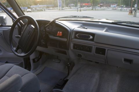1995 Ford Bronco - Interior shot across the gray dash of a 1990s Ford truck, taken from the passenger side looking at the steering wheel, gauge cluster and ro…