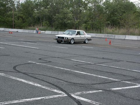 2001 Mercury Grand Marquis - A silver BMW E28 sedan is seen on a paved lot with orange cones and tire marks on the asphalt.