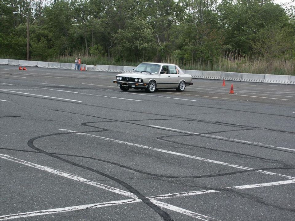 Silver BMW E28 sedan on a paved lot with tire marks