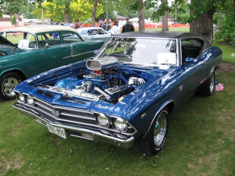 1989 Ford Mustang - A custom blue 1969 Chevrolet SS is displayed with its hood up, revealing a powerful engine, parked next to another vintage car.