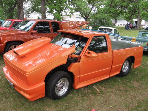 1989 Ford Mustang - Customized orange pickup truck displayed at an outdoor event with other vehicles.