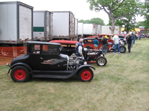 1989 Ford Mustang - A collection of custom cars are displayed outdoors, with several large trailers parked behind them.