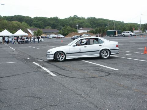 2001 Mercury Grand Marquis - Silver BMW E36 sedan with racing number 5 on door, driver wearing helmet, is seen on a track with tire marks.
