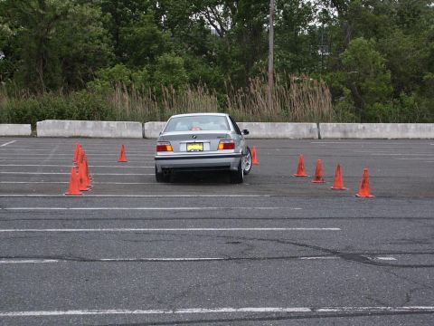 2001 Mercury Grand Marquis - A silver sedan maneuvers through an autocross course marked by orange cones, with its rear clearly visible.