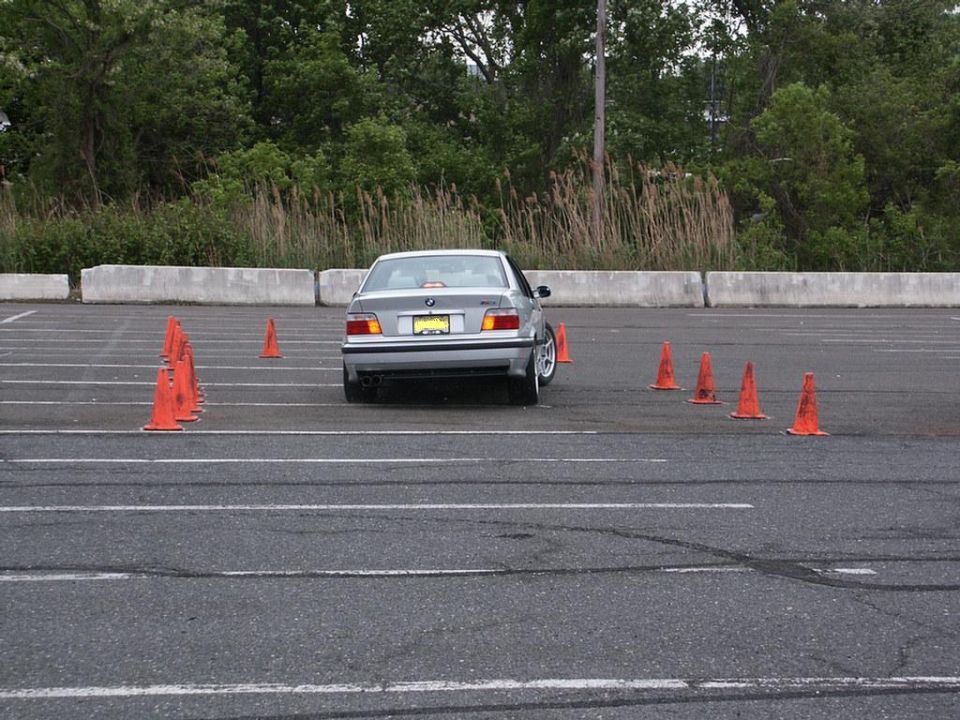 Silver sedan's rear view navigating autocross cones. License plate visible