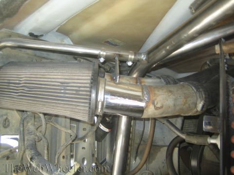 1990 Ford Bronco - polished air intake with cone filter routes into exhaust tubing within a tubular chassis engine bay.
