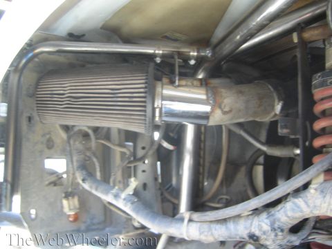 1990 Ford Bronco - cone air filter feeds a chrome intake near a red coil-over shock inside a tube-chassis engine compartment.