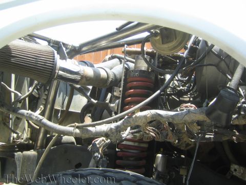 1990 Ford Bronco - tube-chassis engine bay shows a cone air filter, wrapped wiring harnesses and red coil-over suspension springs.