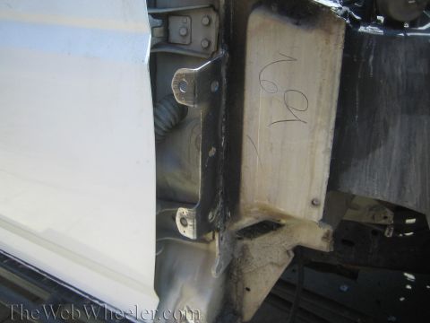 1990 Ford Bronco - Detail of a white vehicle's door jamb and welded body mount bracket with handwritten marks during a build.