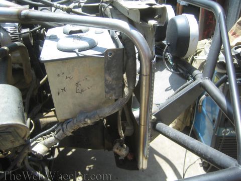 1990 Ford Bronco - Engine bay view showing a fabricated tube chassis, a metal fluid reservoir with handwritten notes, and routed wiring.