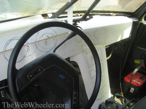 1990 Ford Bronco - Interior shot of a Ford steering wheel and a handwritten paper dash template inside a gutted cab with a red battery.