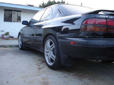 1989 Mazda MX-6 - Rear quarter view of a black 1989 Mazda MX-6 GT with a spoiler and aftermarket wheels.